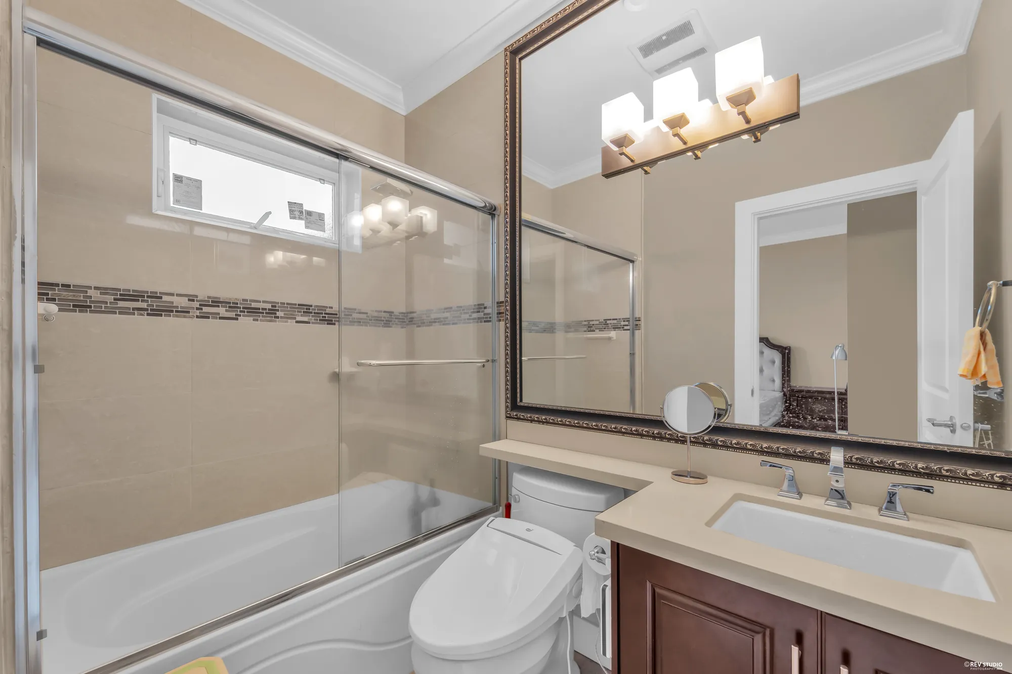 A bathroom with a tub and shower behind glass, a granite vanity under a wide mirror