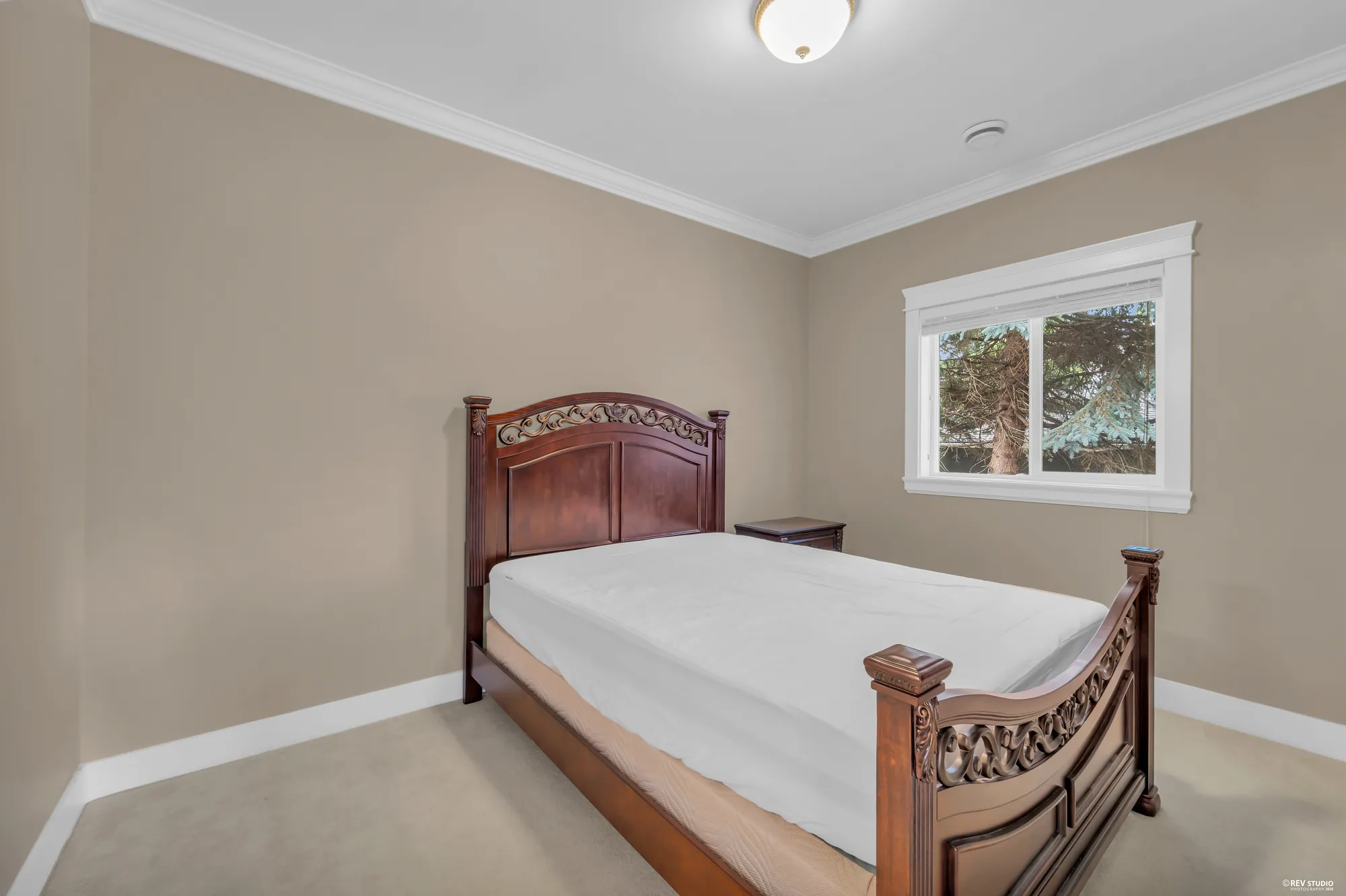 A bedroom with a carved wooden bed and a window