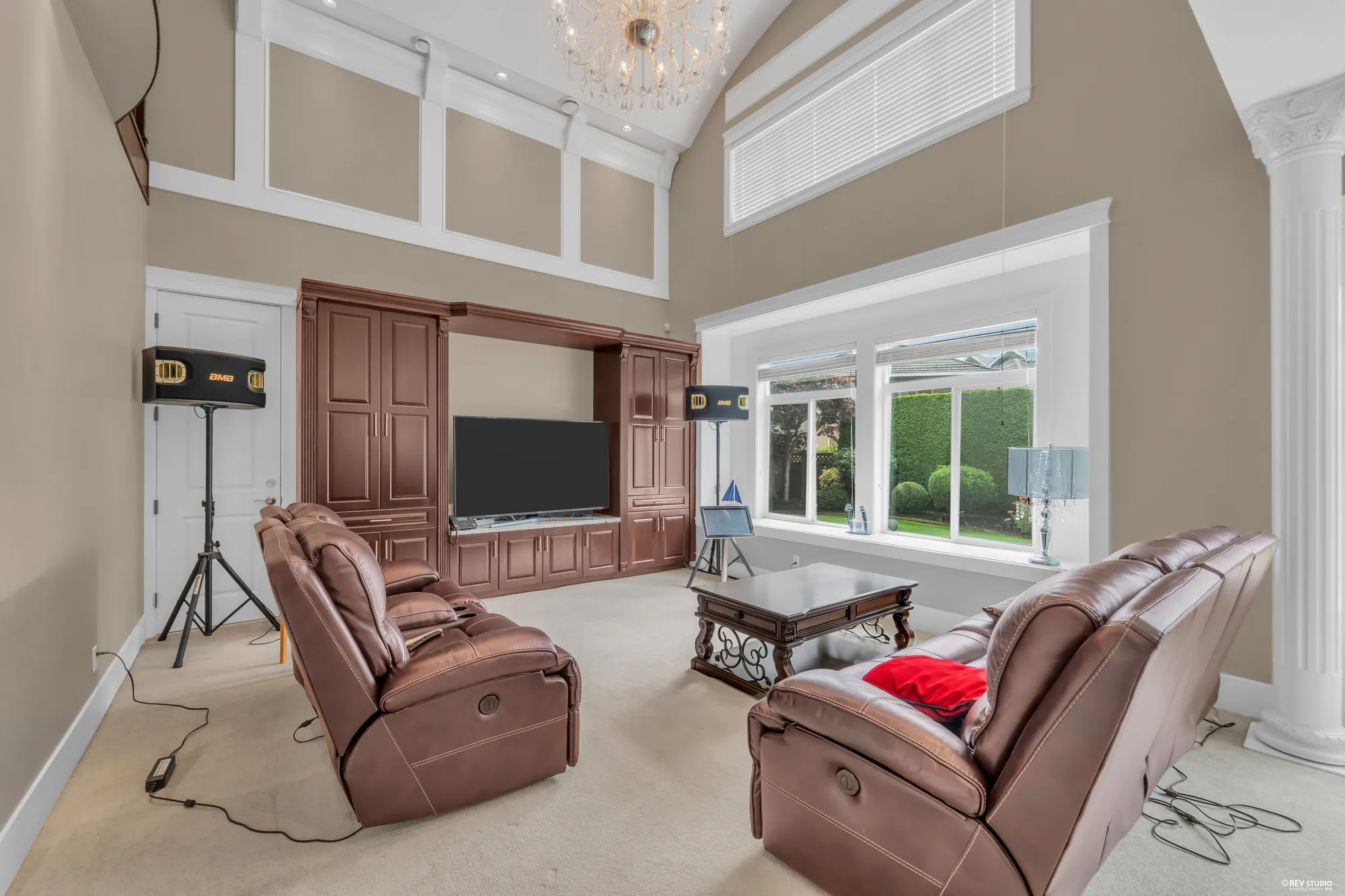 The family room open to the roof: leather sofas, a cherry television cabinet, a wide window onto the garden