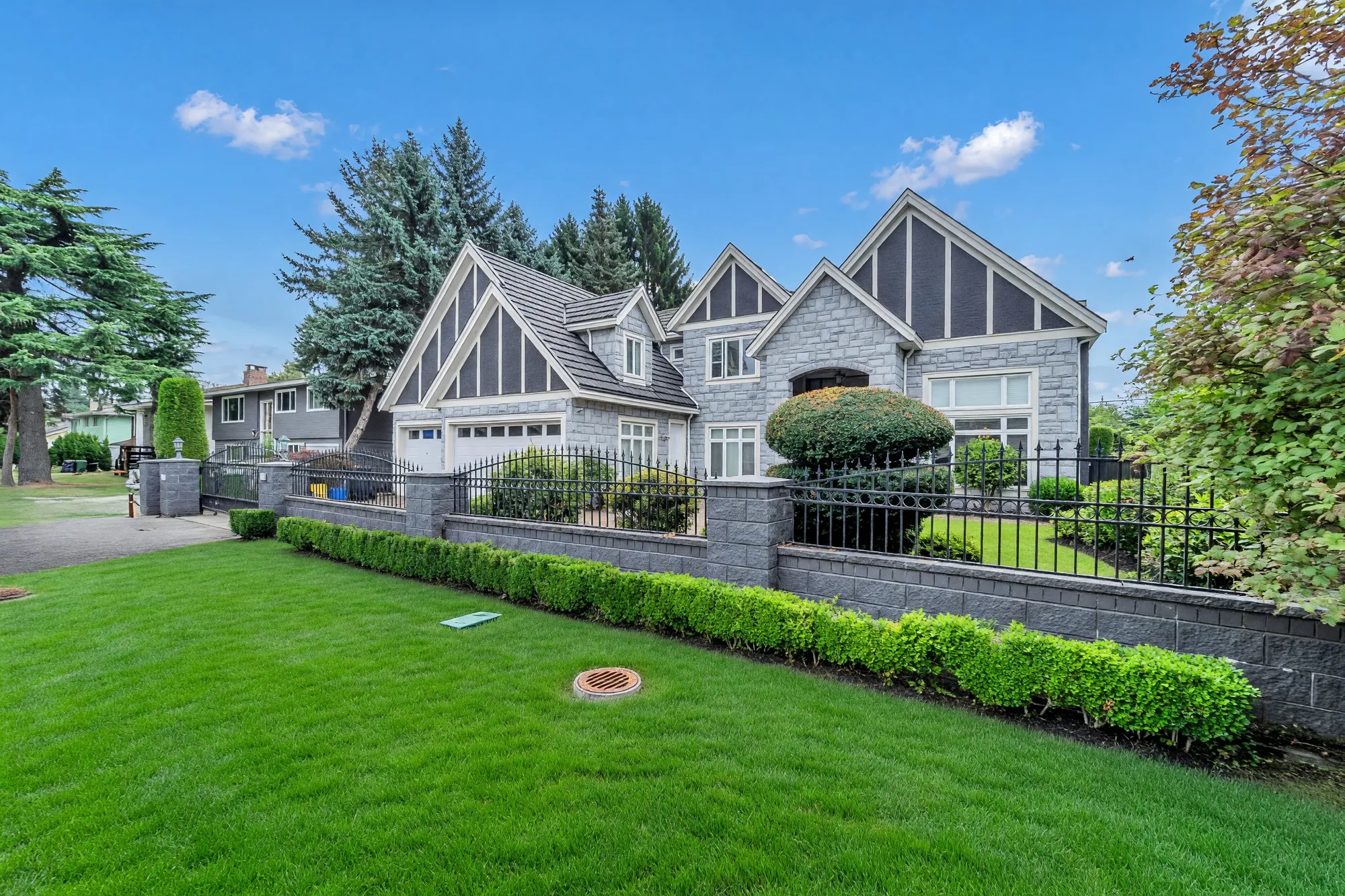 The house from the corner of the street, the fence and hedge running along the boulevard