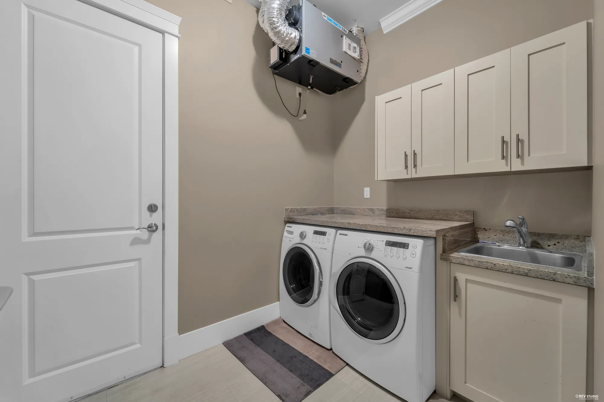 The laundry room: a washer and dryer under cabinets, a sink, the heat-recovery unit above