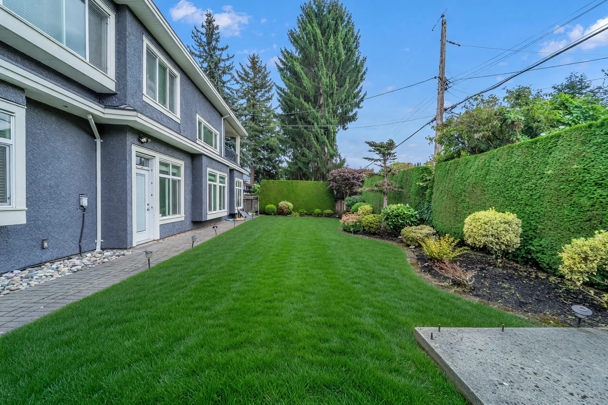 The side lawn between the house and the hedge, a bed of shrubs along the hedge