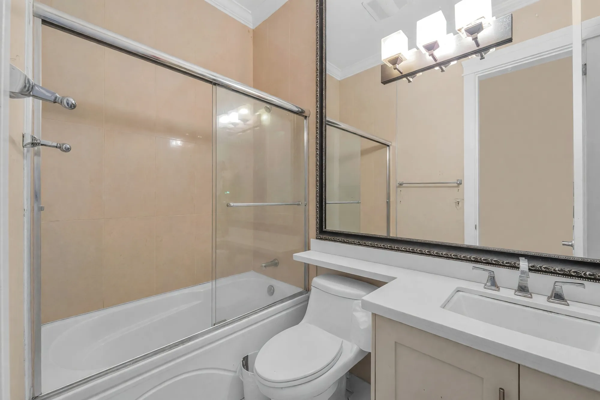 The wing's bathroom: a tub and shower behind glass, a vanity under a framed mirror