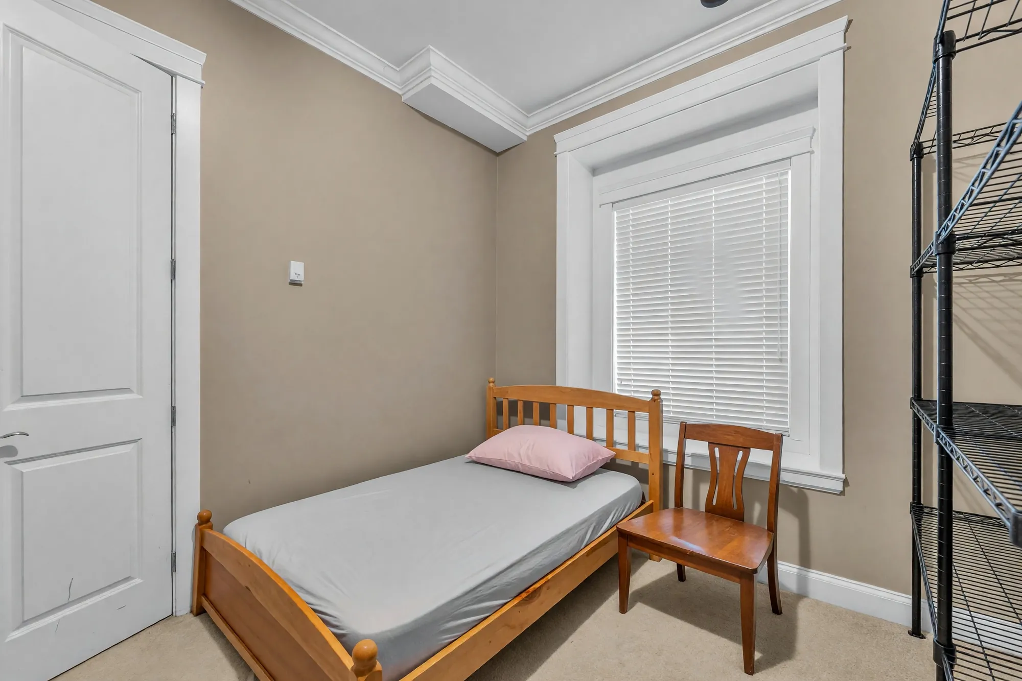 The wing's bedroom: a single bed under the window, a metal shelving unit