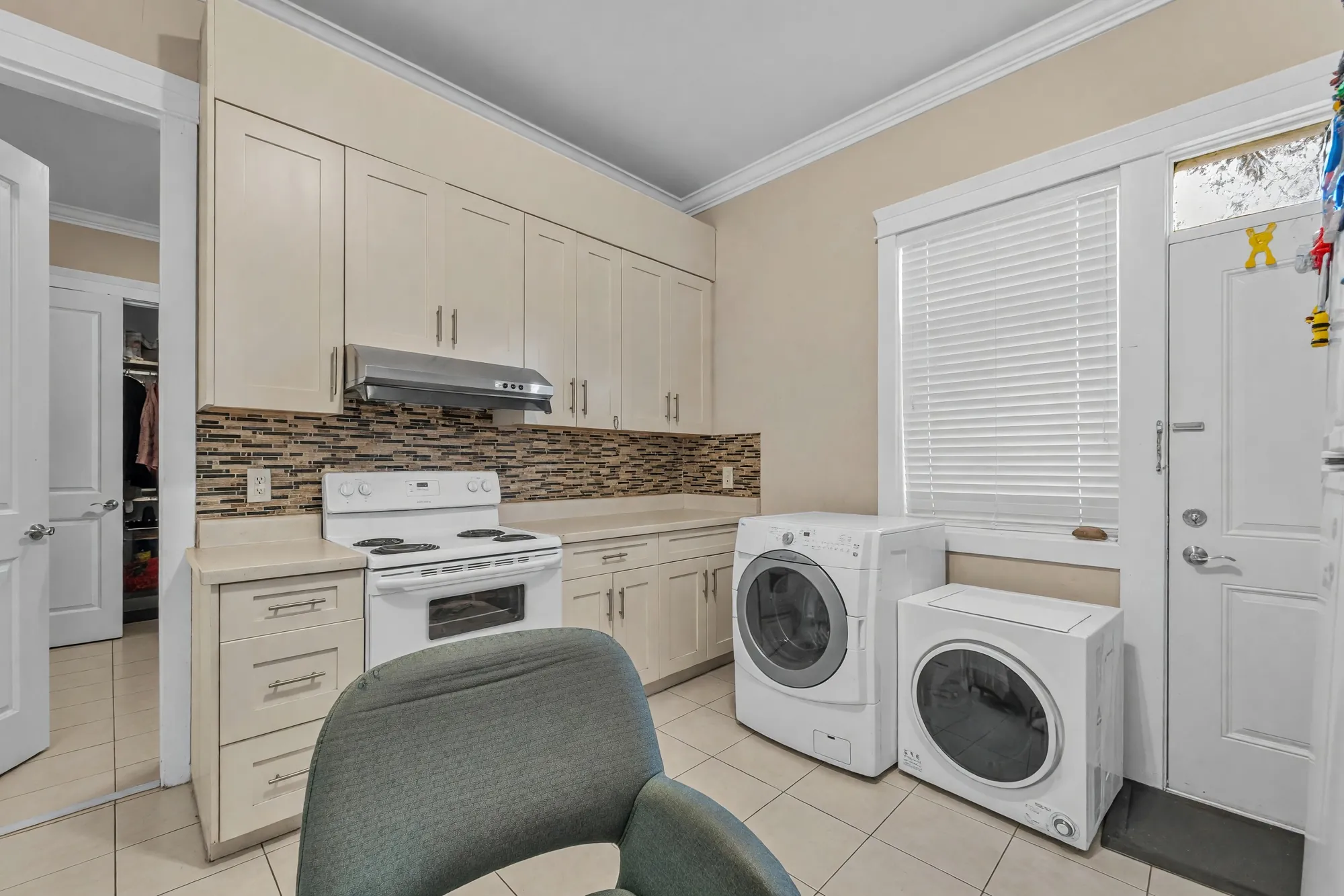 The second kitchen in the wing: cream cabinets, a range, a washer and dryer, its own door to the outside
