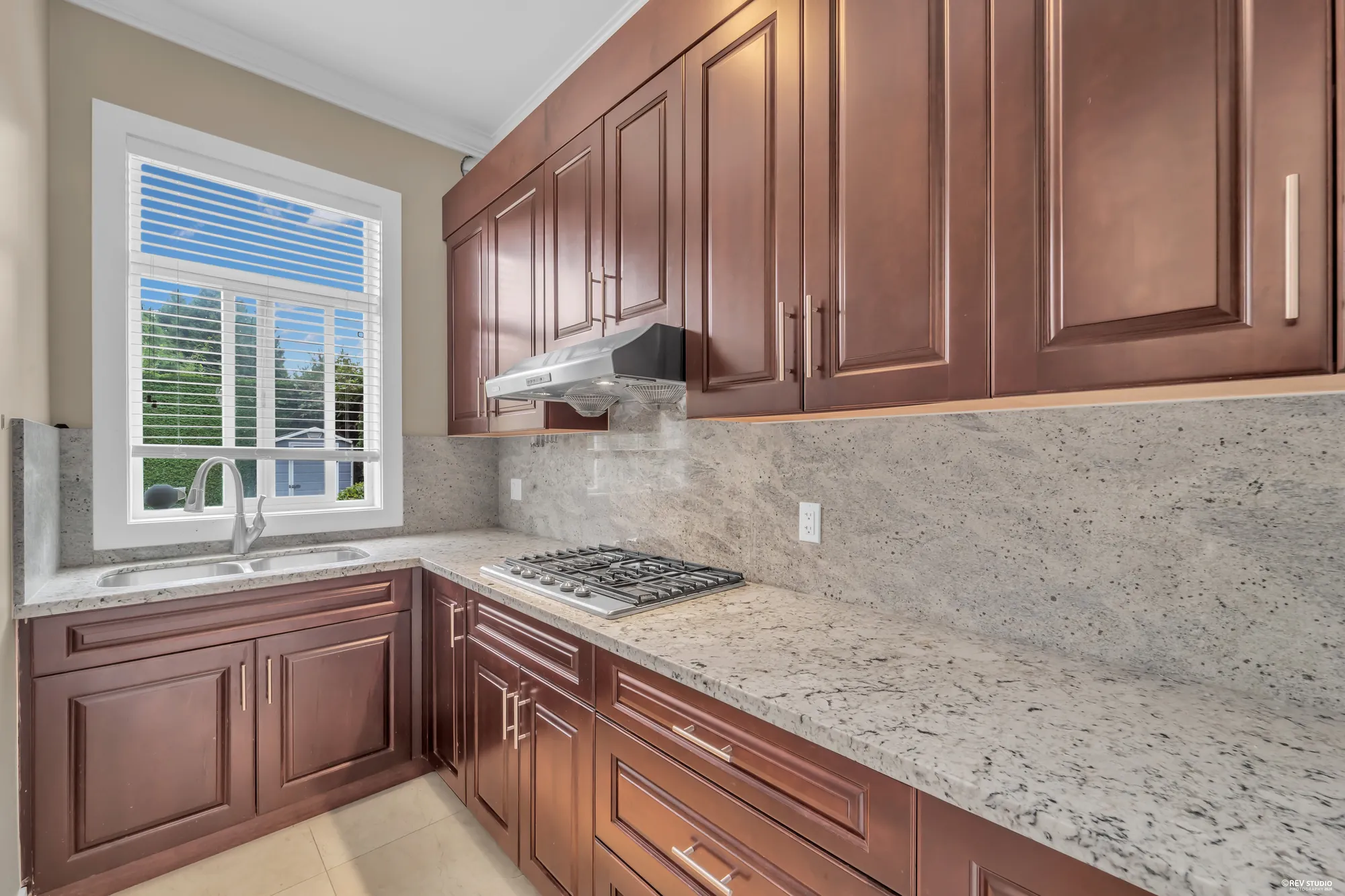 The wok kitchen: cherry cabinets, a gas cooktop under its hood, a window over the sink